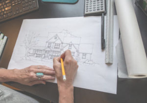 Person sketching and designing the exterior of a house