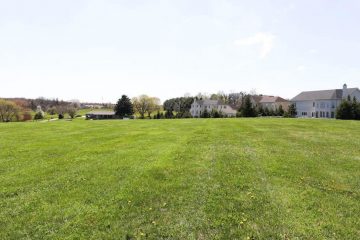 Large Grassy Area With Homes in Background