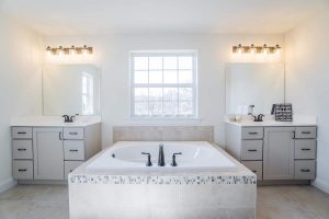 Full bathroom with two sinks and a marble bathtub in between them