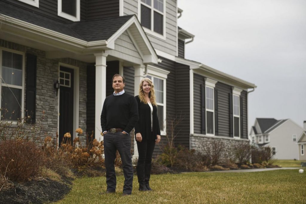 Two People Standing in Front of a newly built House