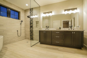 Full bathroom with large shower and two sinks with brown cabinets